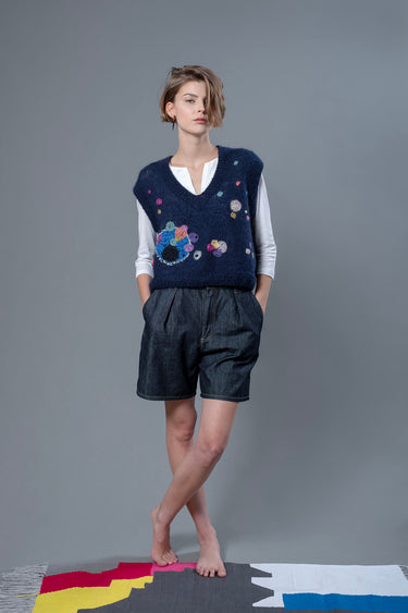 Woman wearing mohair navy vest. The vest is adorned with abstract star-like colourful embroideries